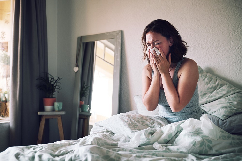 Woman in bed blows her nose