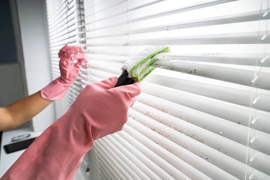 Someone wearing pink rubber gloves cleans their blinds