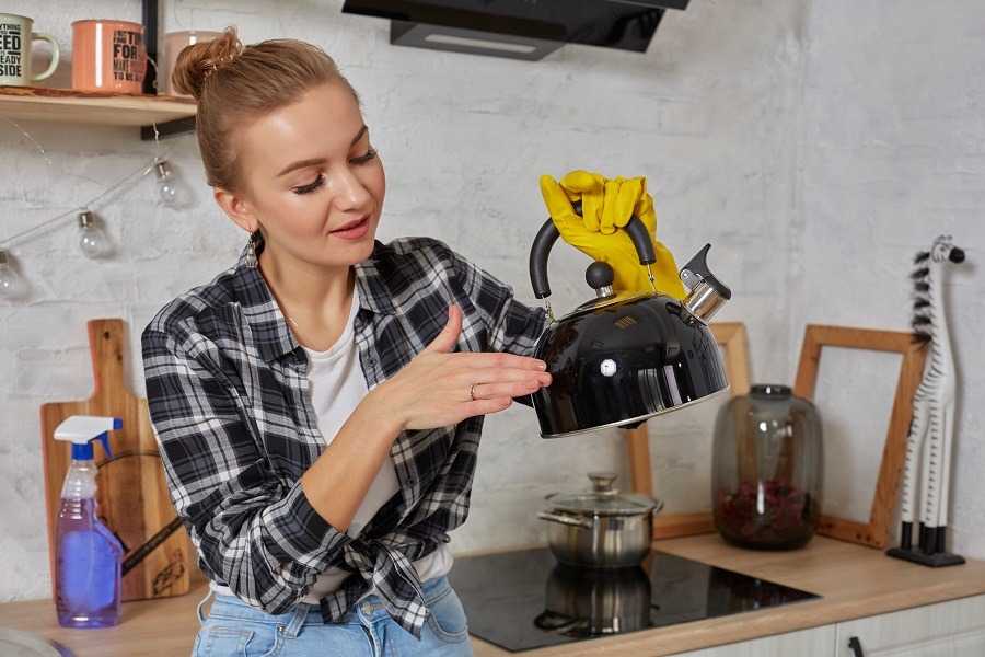 Woman in checkered shirt shows off her clean, black kettle