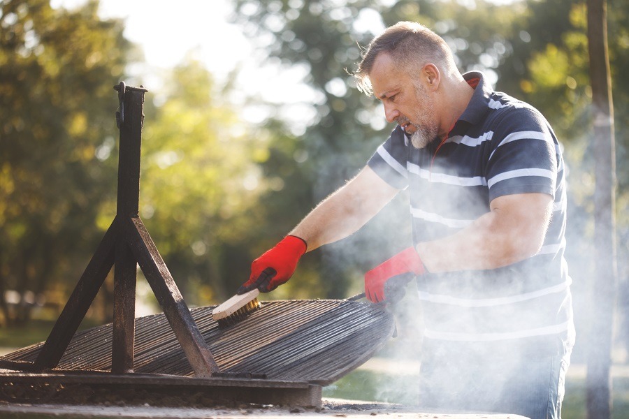 Man in red rubber gloves cleaning his bbq