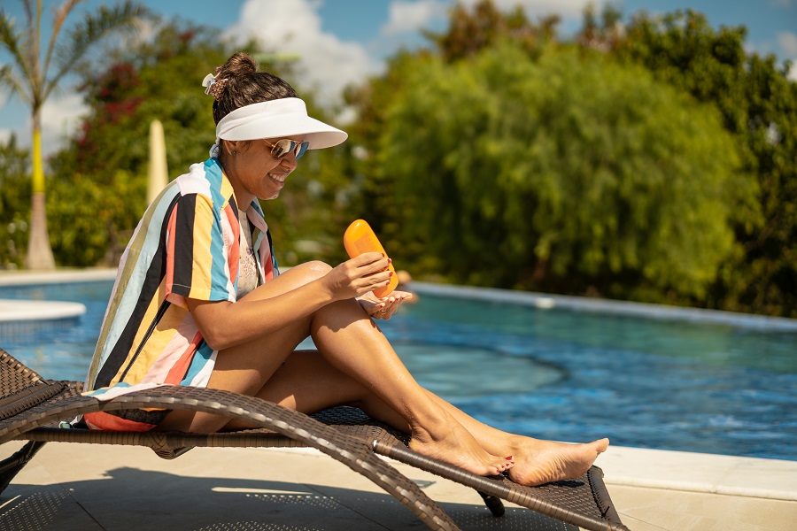 Lady by the pool applies suncream to her legs