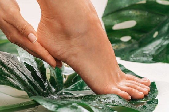smooth pedicured feet on wet leaves